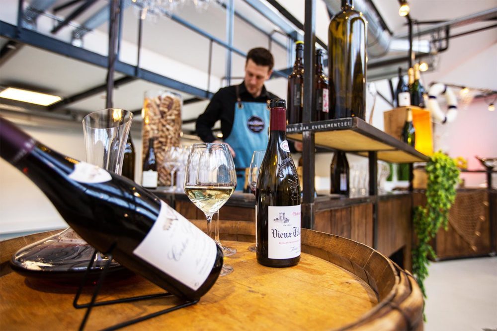 A bottle of wine on a barrel with a waiter hired for the event